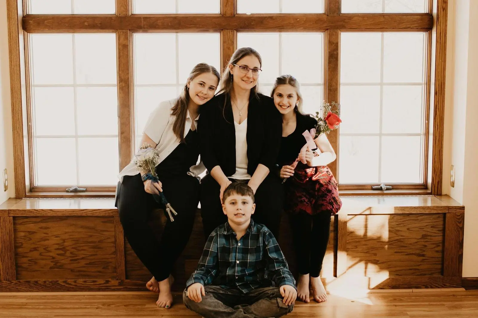 A family posing for a picture in front of a window.